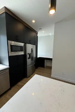 Client photo of a clean kitchen with polished fridge and microwave after a WhiteBox move-out clean